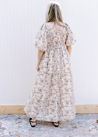 Back view of a cream short sleeve dress with brown floral, square neck and smocked bodice. 