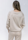 Back view of Model wearing a classic taupe sweatshirt with a round neck and long sleeves.