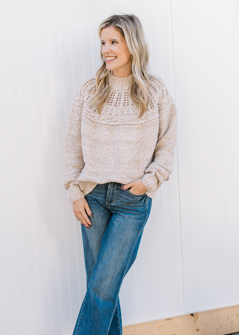 Model wearing an oatmeal sweater with open knit yolk detail, mock neck and long sleeves. 