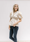 Model wearing a cream top with an elastic waistband, v-neck with a ruffle detail and short sleeves. 