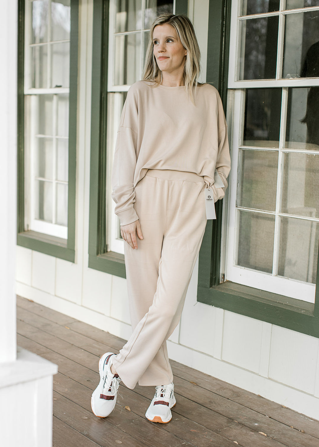 Model wearing a cream matching set with a slightly cropped long sleeve top and straight leg pants. 