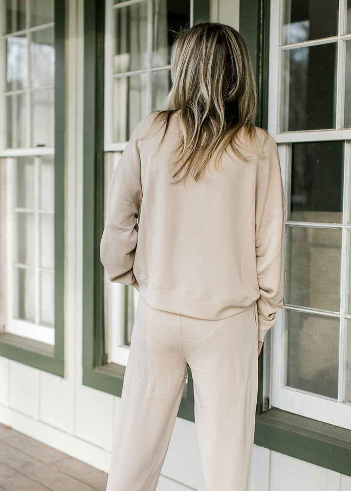 Back view of Model wearing a cream set with a slightly cropped top and straight leg pants. 