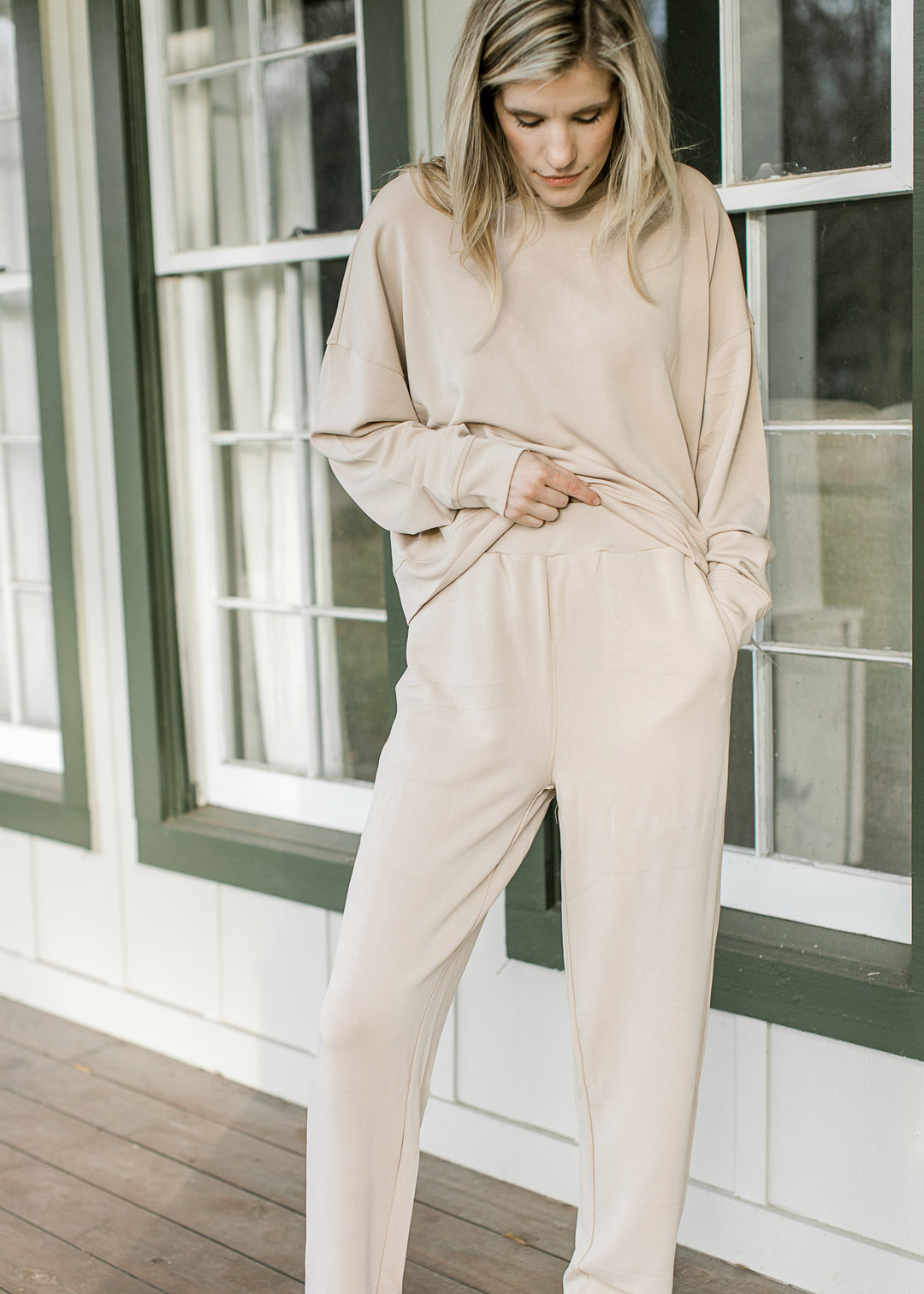Model wearing a matching cream set with elastic waist, straight leg pants and long sleeve top. 
