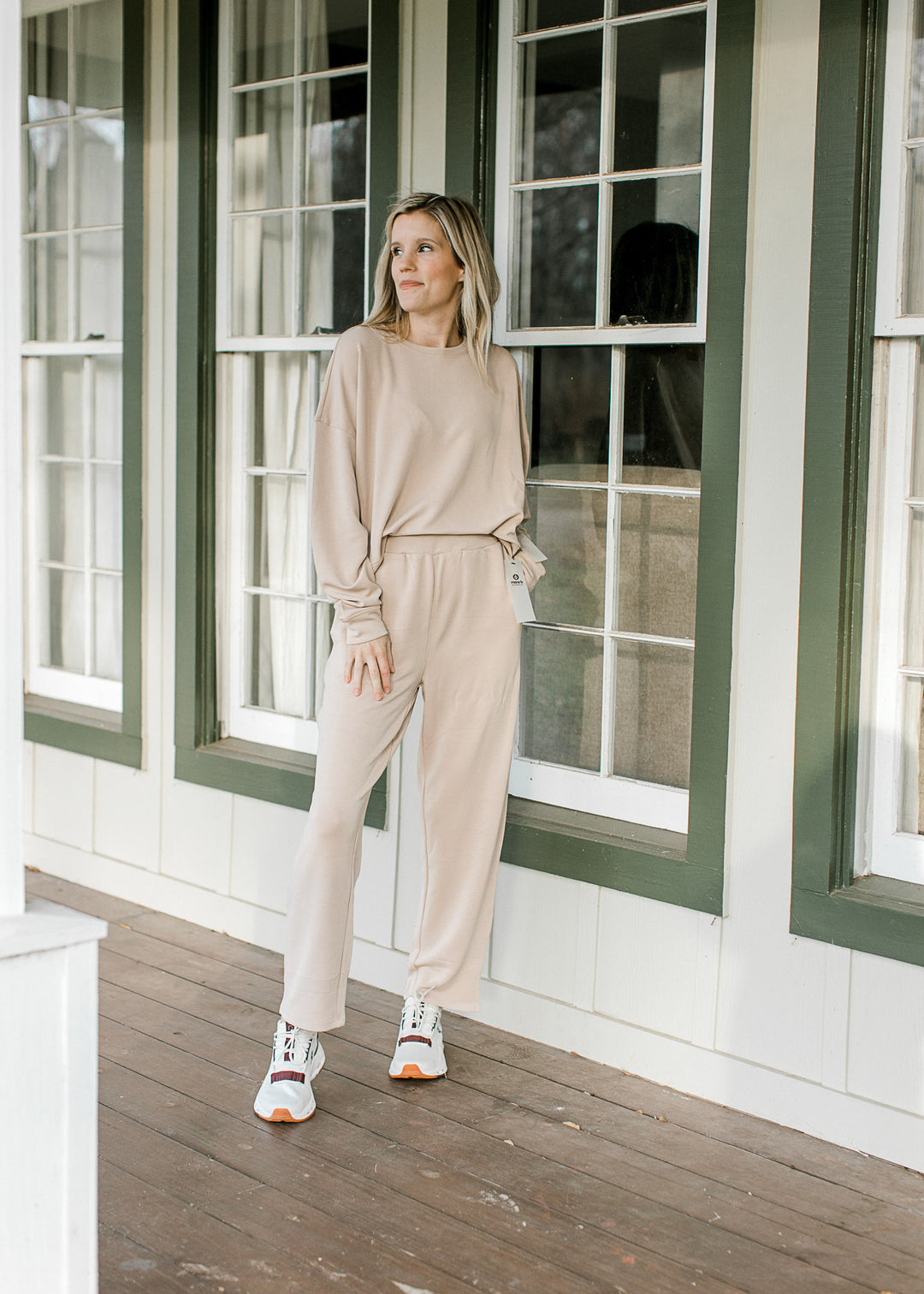 Model wearing a cream set with a slightly cropped long sleeve top and straight leg pants. 