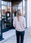 Back view of Model wearing a wheat sweater with long sleeves and ribbed neck, hem and cuff. 