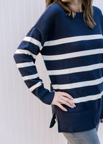 Close up of long sleeve and extended shoulder on a navy sweater with cream stripes. 