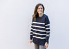 Model wearing a navy sweater with white stripes, long sleeves and split sides.