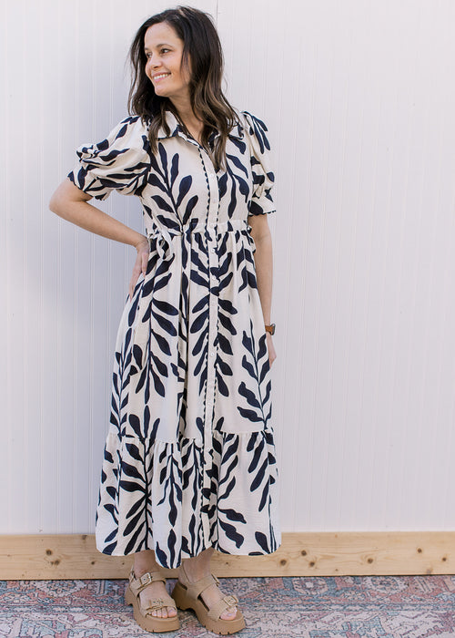 Model wearing a white dress with navy floral, bubble short sleeves and a scalloped detail.