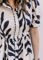 Close up of collar, scalloped detail and short puff sleeves on a white maxi with navy floral.