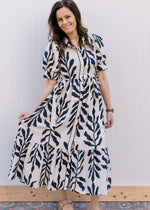 Model wearing a white dress with navy floral, bubble short sleeves and a tie at the waist.