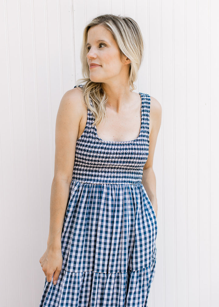 Close up of smocked bodice and straps on a navy and white sleeveless gingham maxi dress.