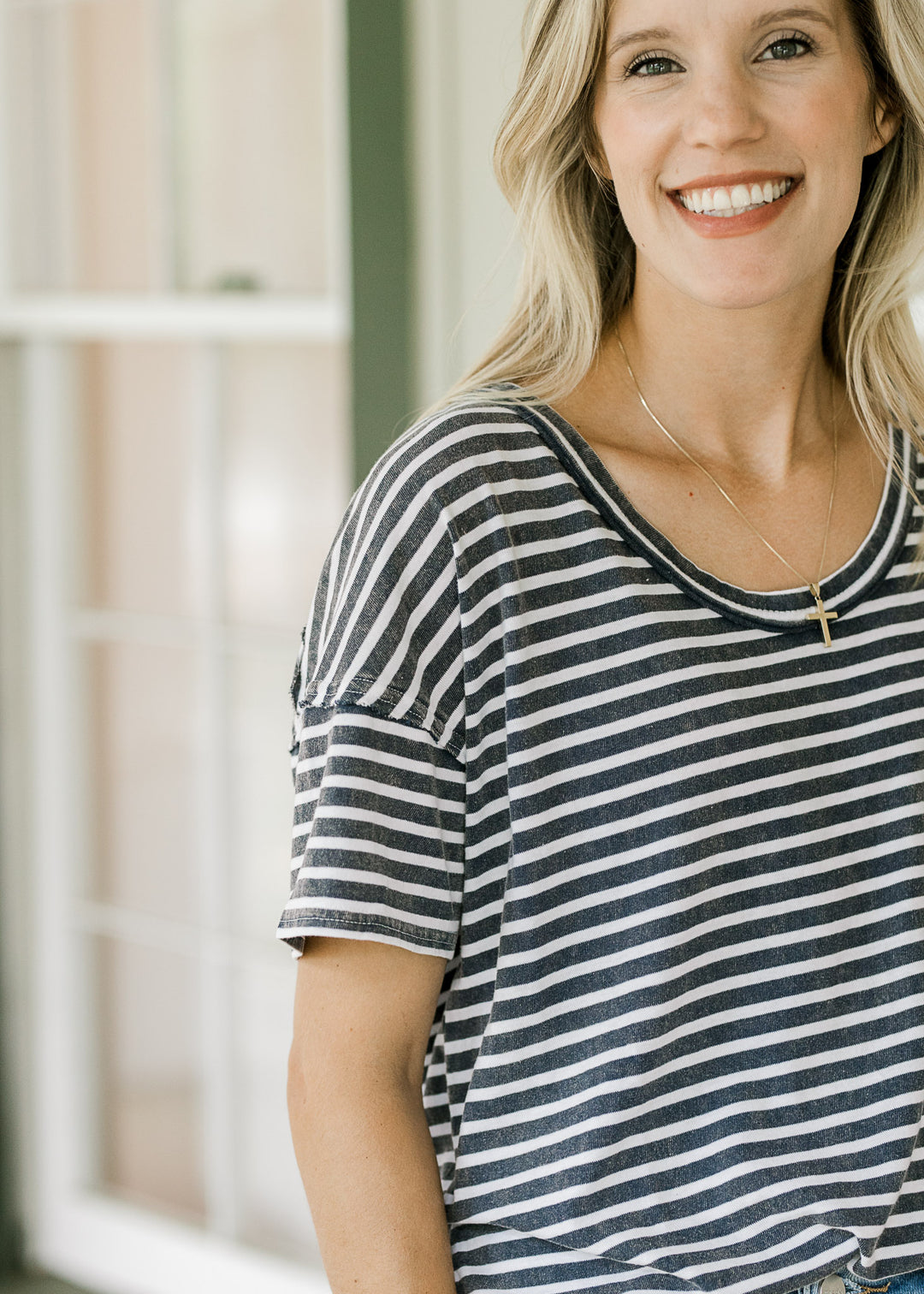 Model wearing a scoop neck tee with navy and white stripes, short sleeves and a loose fit. 