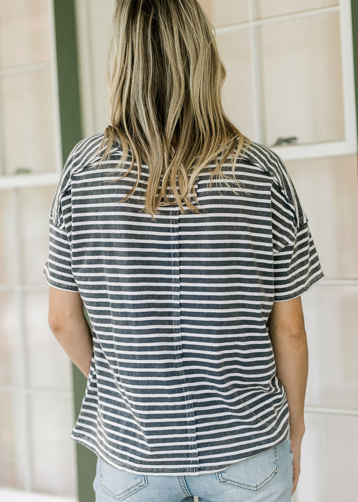 Back view of Model wearing a navy and white striped tee with short sleeves and seem up back. 