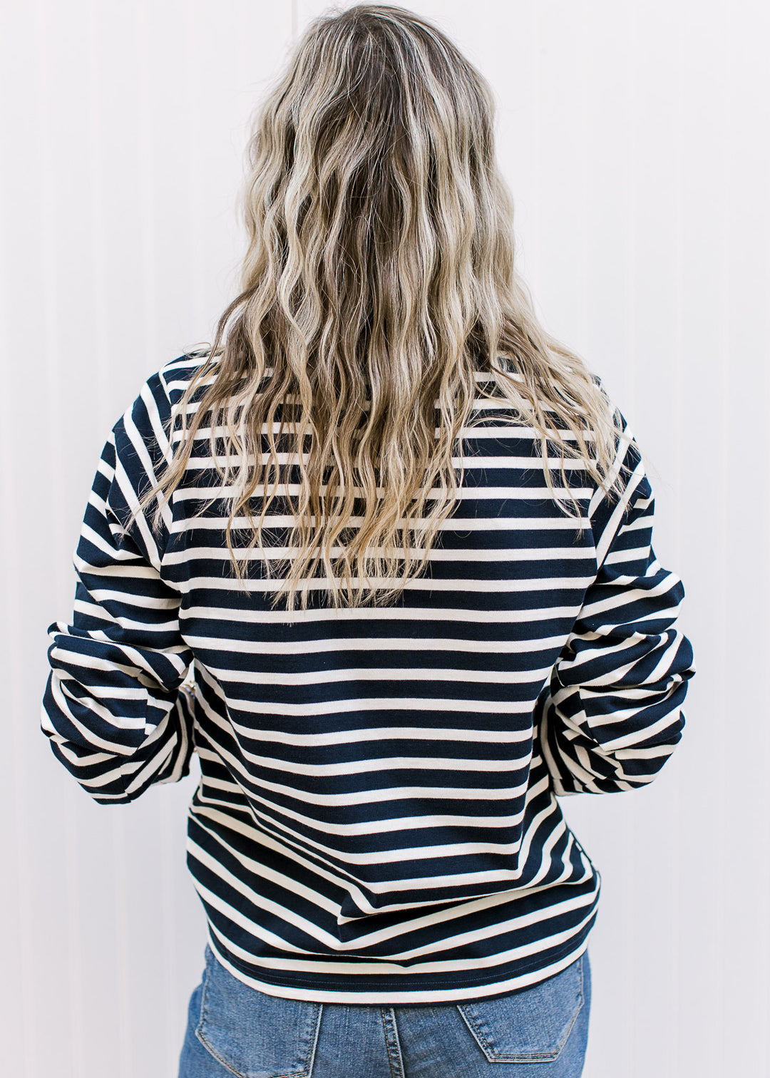 Back view of Model wearing a navy and white stripped top with a round neck and long sleeves. 