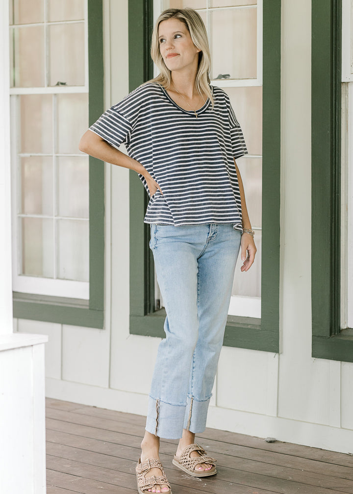 Model wearing a navy and white striped tee with short sleeves, scoop neck and jeans. 