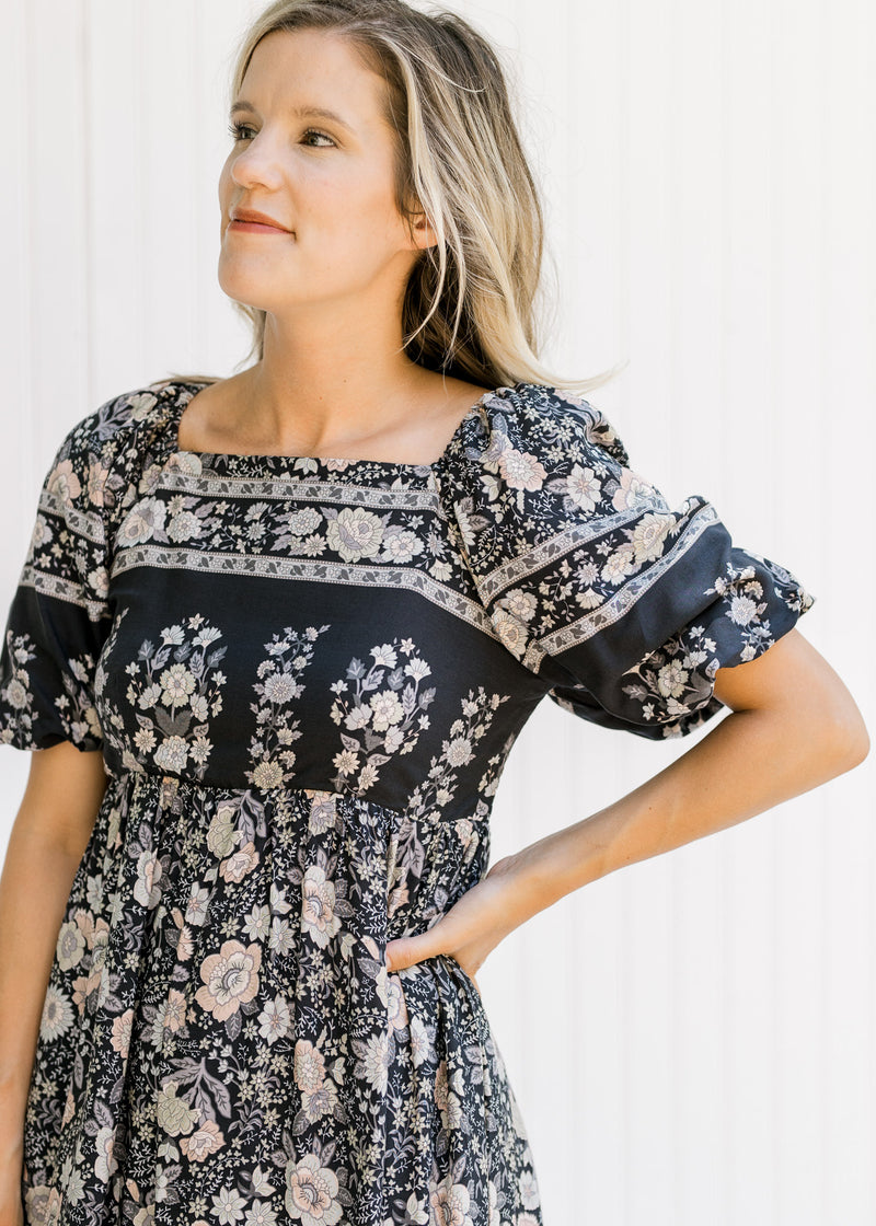 Close up of square neck and short puff sleeves on a navy midi dress with a floral pattern. 