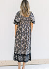Back view of smocked back on a navy midi dress with a floral pattern and short puff sleeves.