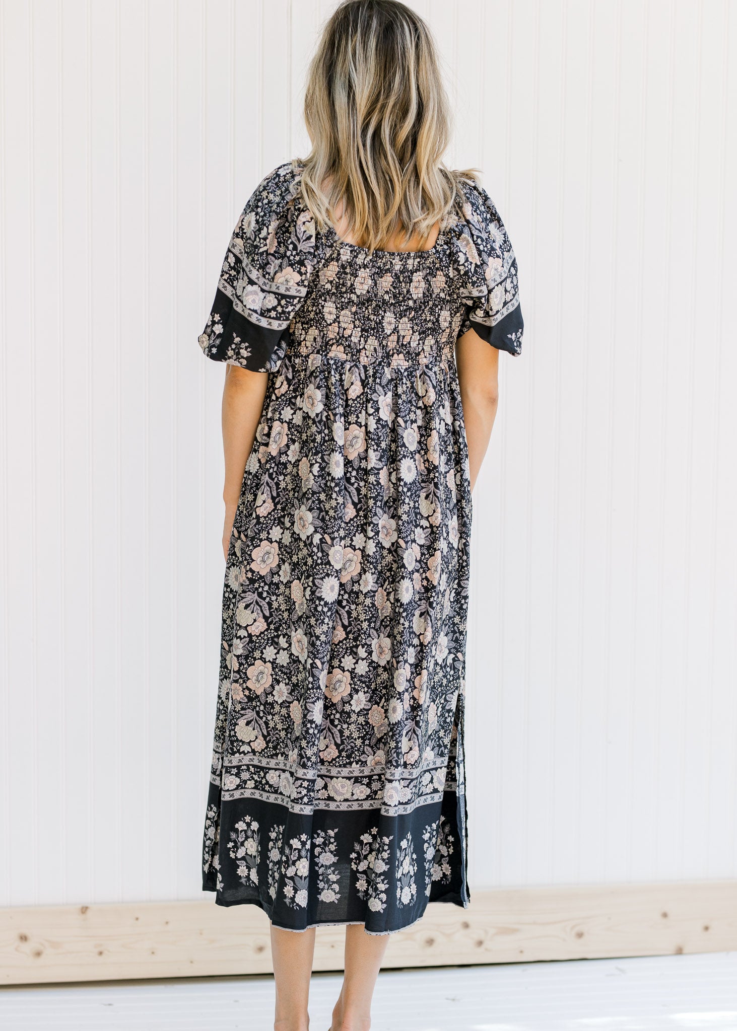 Back view of smocked back on a navy midi dress with a floral pattern and short puff sleeves.