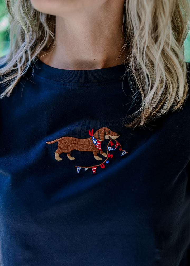 Close up of embroidered Dachshund with USA banner on a navy short sleeve top with short sleeves.
