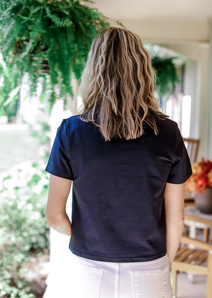 Back view of Model wearing a navy top with slightly cropped fit, round neck and short sleeves.
