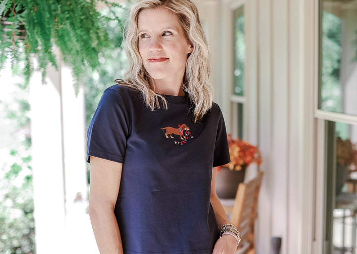 Model wearing a navy slightly cropped top with an embroidered dog, round neck and short sleeves.