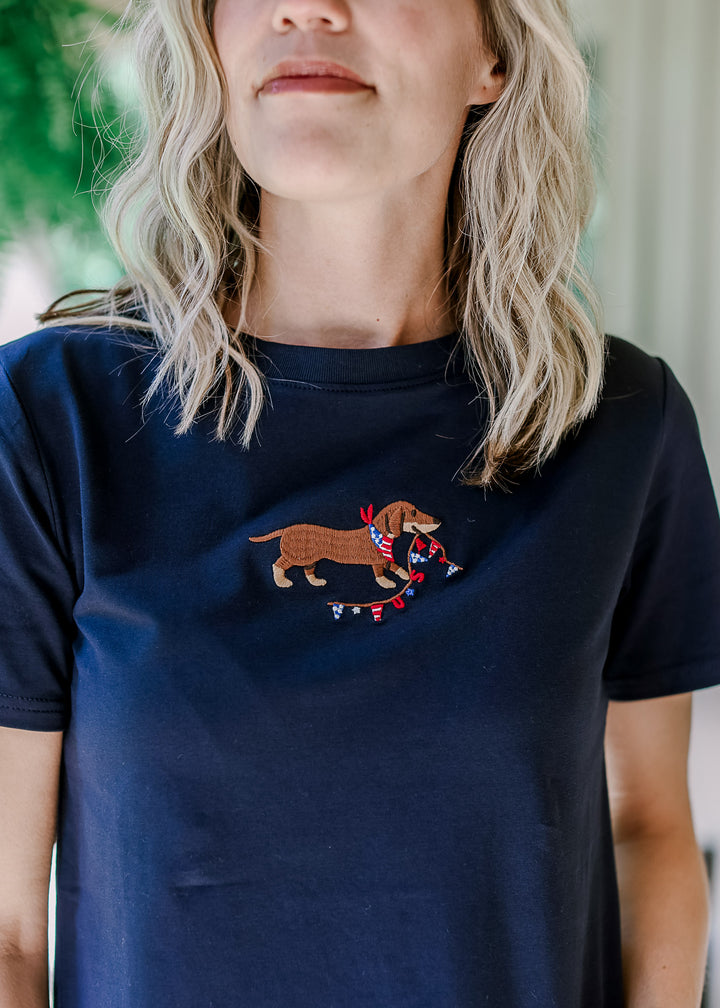 Model wearing a navy short sleeve top with an embroidered Dachshund and round neck. 