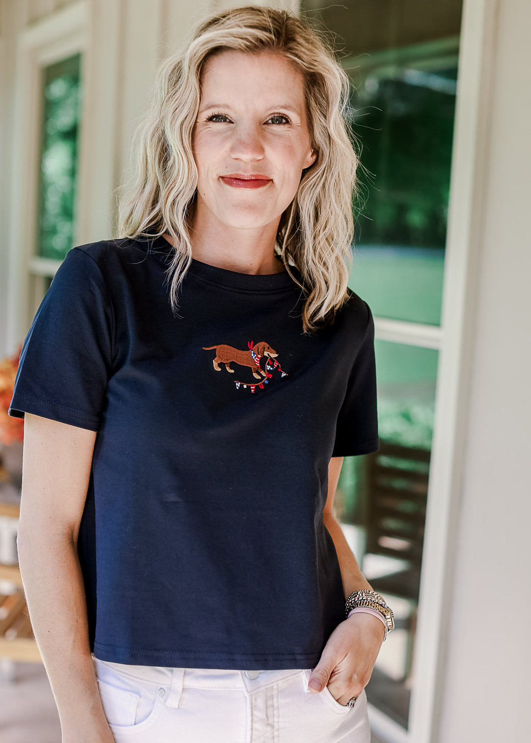 Model wearing white pants and a navy top with an embroidered dog, round neck and short sleeves.