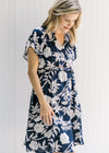Model wearing a navy above the knee dress with a white floral pattern and short sleeves. 