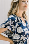 Close up view of model waring a navy dress with a white floral pattern and ruffles along the tiers. 