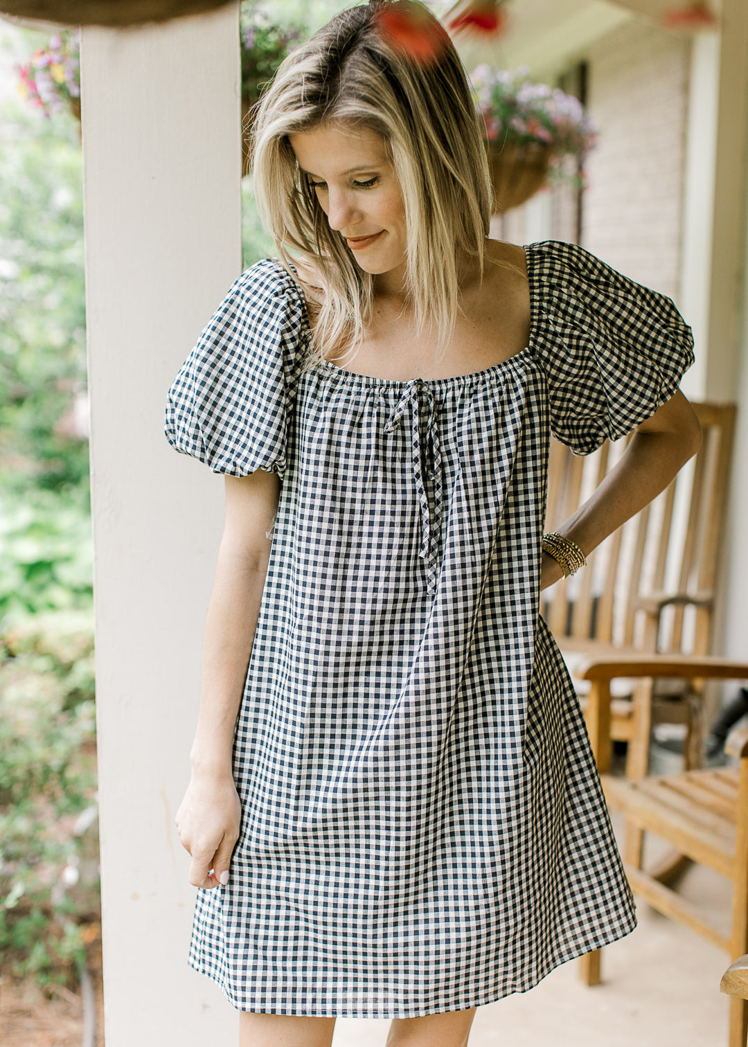 Model wearing a navy and cream gingham dress with square neck with elastic and bubble sleeves. 