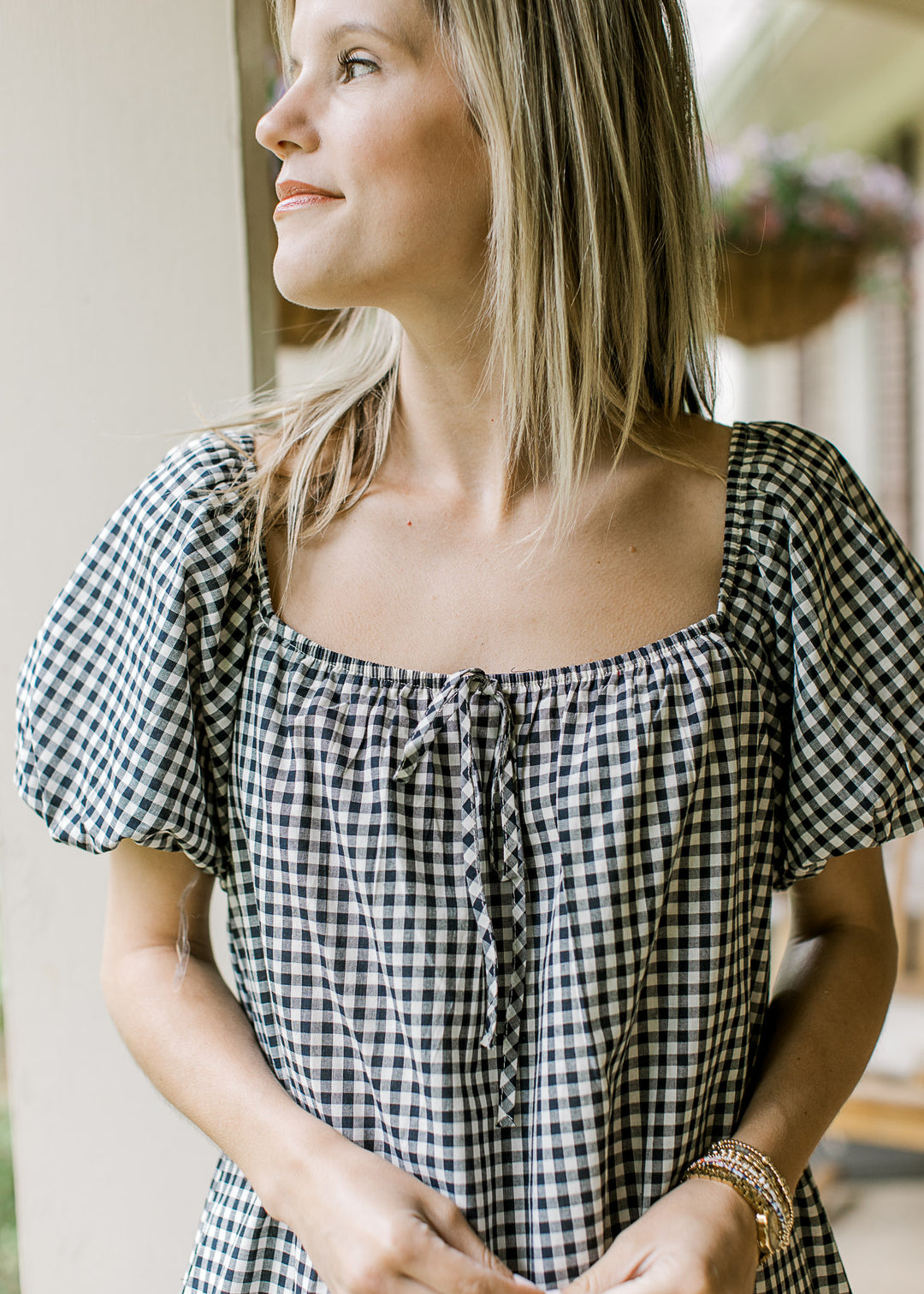 Close up of square neck with faux tie at neck and bubble short sleeves on a navy and cream gingham.