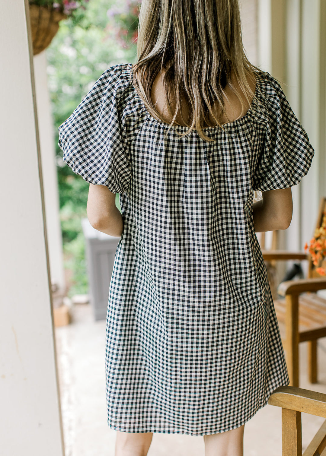 Back view of Model wearing a navy and cream gingham dress with square neck and bubble sleeves.