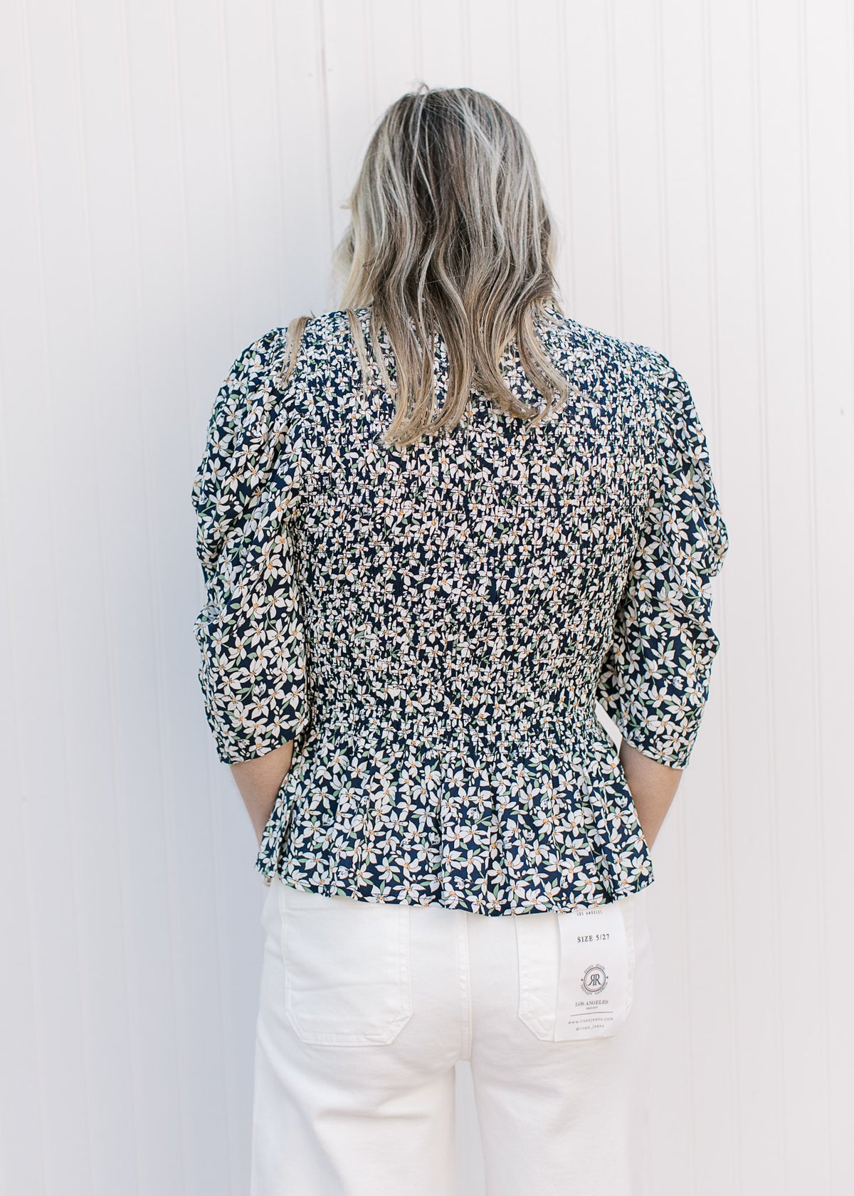 Back view of Model wearing a navy top with micro-floral print and elbow length sleeves.