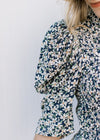 Close up of elbow length sleeves with pleated shoulder and smocked  bodice on a navy floral top.
