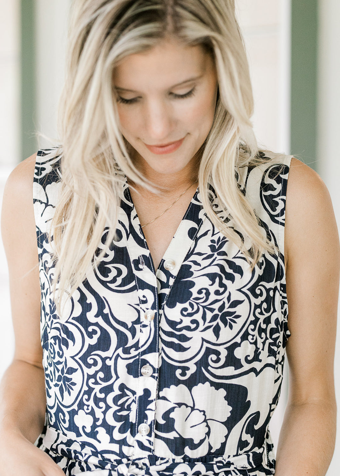 Model wearing a navy maxi with cream floral pattern, v-neck, tie at waist and pockets. 