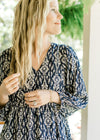 Close up of v-neck and 3/4 sleeve with elastic band on a navy dress with taupe floral. 
