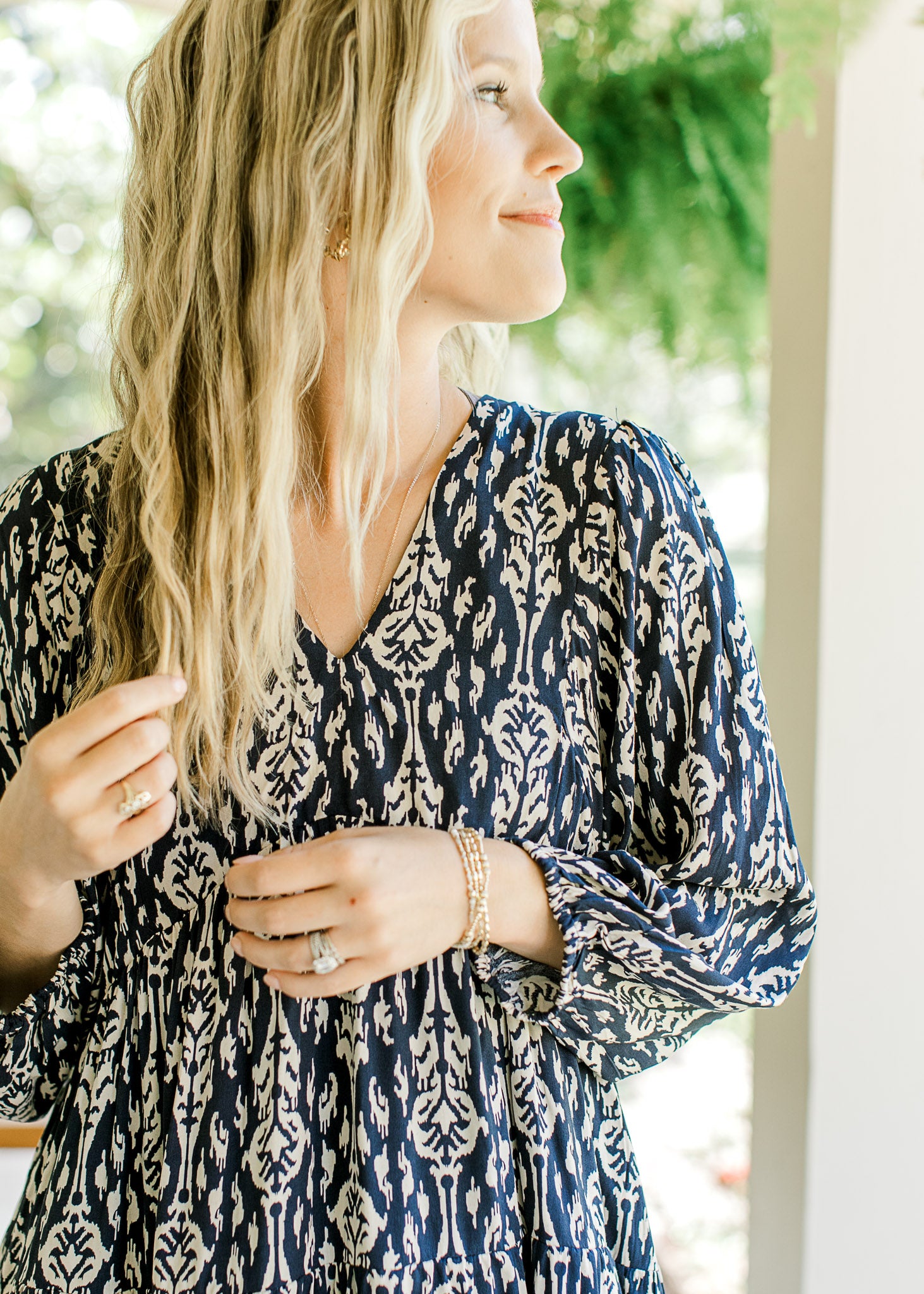 Close up of v-neck and 3/4 sleeve with elastic band on a navy dress with taupe floral. 