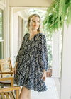 Model wearing a navy above the knee dress with taupe floral pattern and 3/4 sleeve. 