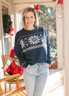 Model wearing a navy sweater with a  snowflake pattern, long sleeves and a round neck.