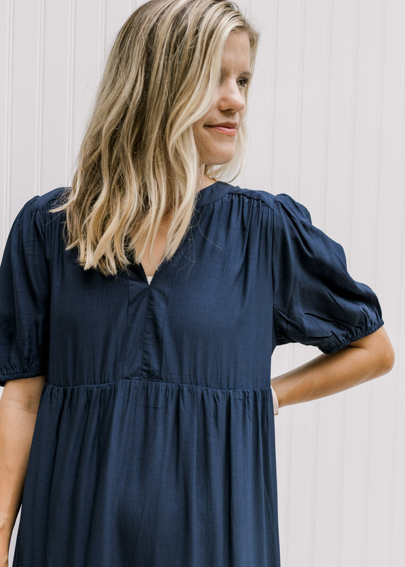 Close up of v-neck and bubble short sleeves on a model wearing a navy tiered dress.