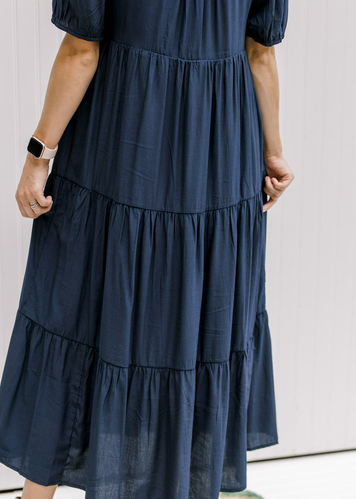 Close up of the tiers on a model wearing a navy dress with bubble short sleeves.