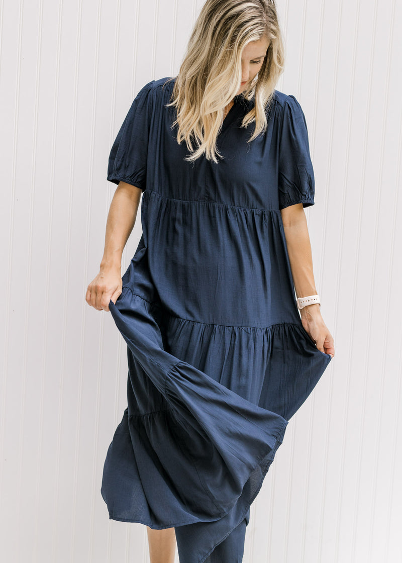 Model wearing a tiered navy midi dress with a v-neck and bubble short sleeves.