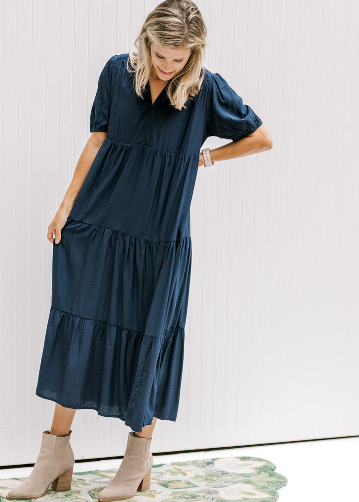 Model wearing tan booties with a tiered navy dress with a v-neck and bubble short sleeves.
