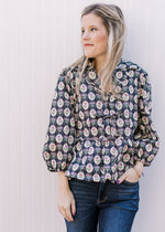 Model wearing a navy top with cream, pink and blue floral pattern and tie front closure.