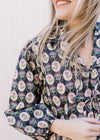 Close up of 3/4 sleeves, collar and tie closure on a navy top with cream, pink and blue floral. 