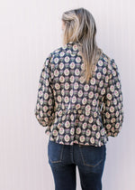 Back view of Model wearing a navy top with cream, pink and blue floral pattern and tie front closure