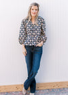 Model wearing jeans and a navy top with cream, pink and blue floral pattern and tie front closure