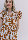 Close up of v-neck and ruffle short sleeves on a cream cotton dress with a rust floral pattern. 