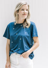 Model wearing a navy top with cream embroidered stars a round neck and short sleeves. 