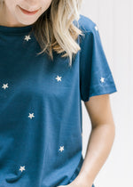 Close up of cream emboldened stars on a navy short sleeve top with a round neck. 